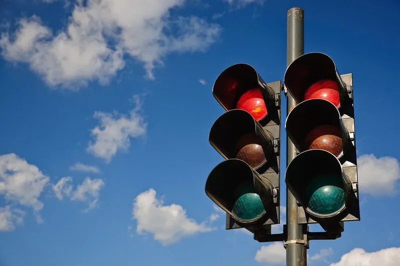 “A couple of red traffic lights against a blue sky” by Horia Varlan